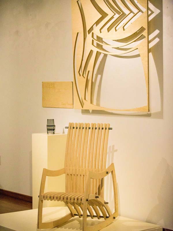 a wooden rocking chair is on display in an art gallery