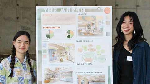 two women standing next to a poster with information on it