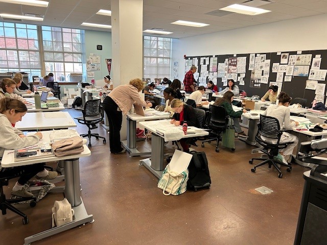a group of people sitting at desks in a classroom