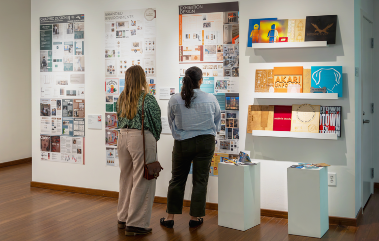 Two women look at a display of posters and other materials