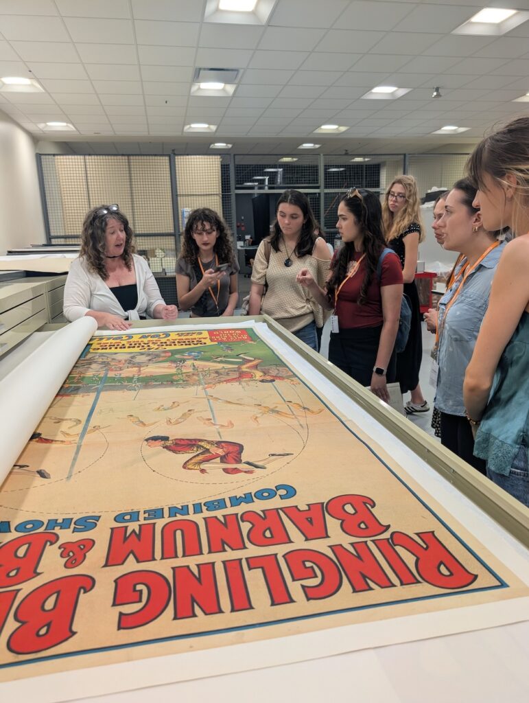 people look at an old circus poster in a museum archive