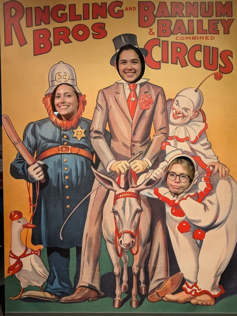 Young people pose in a cutout display of clowns