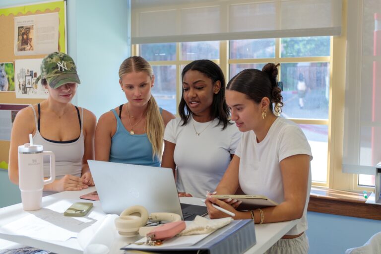 young women working at a computer together,