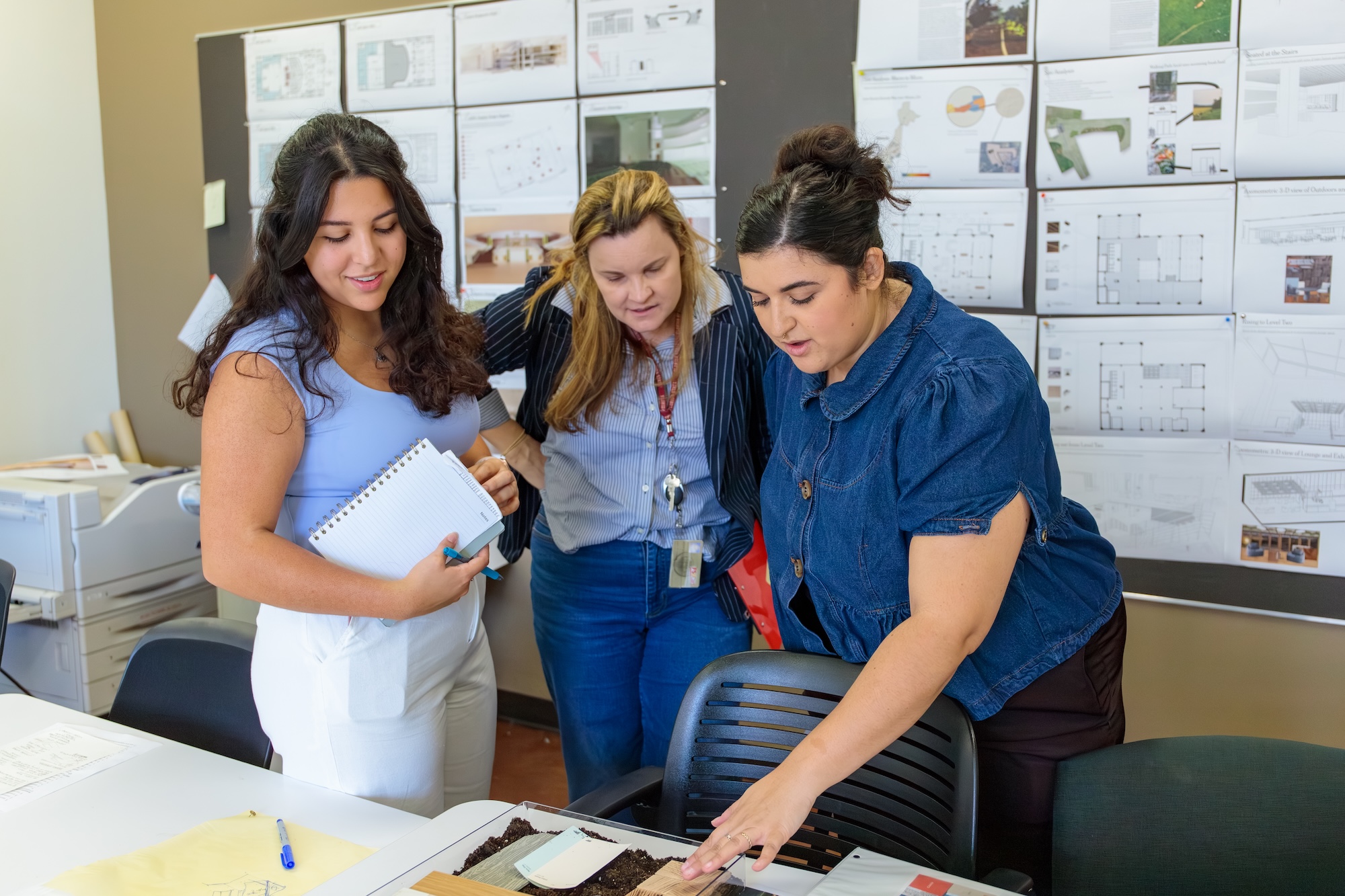 Three women examine work on a table